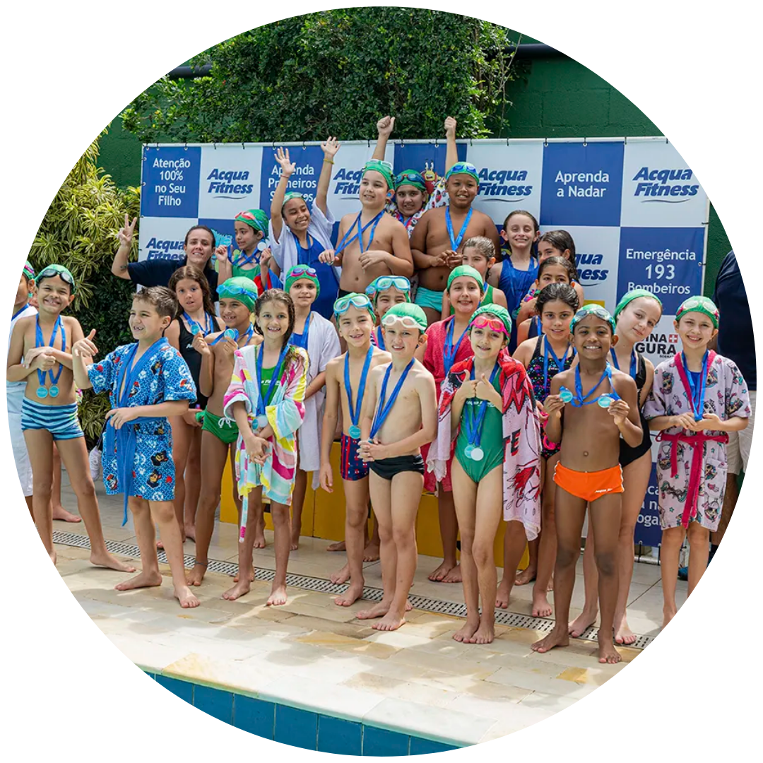 Grupo de crianças felizes a exibir as suas medalhas no pódio durante um festival de natação infantil promovido pela academia Acqua Fitness, no Recreio dos Bandeirantes.
